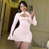 Woman in a light pink dress taking a mirror selfie in an indoor setting.